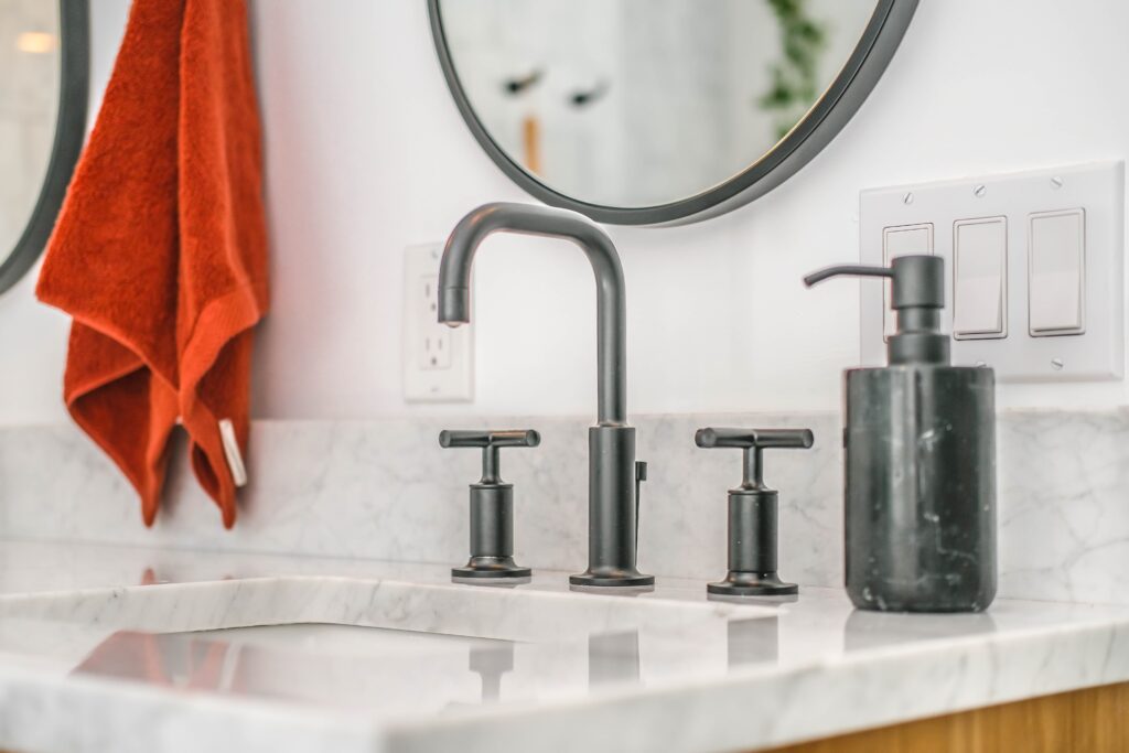 bathroom sink with faucet, mirror, towel & soap dispenser