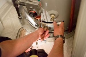 A man uses a flashlight to help him see the water heater in a dark closet